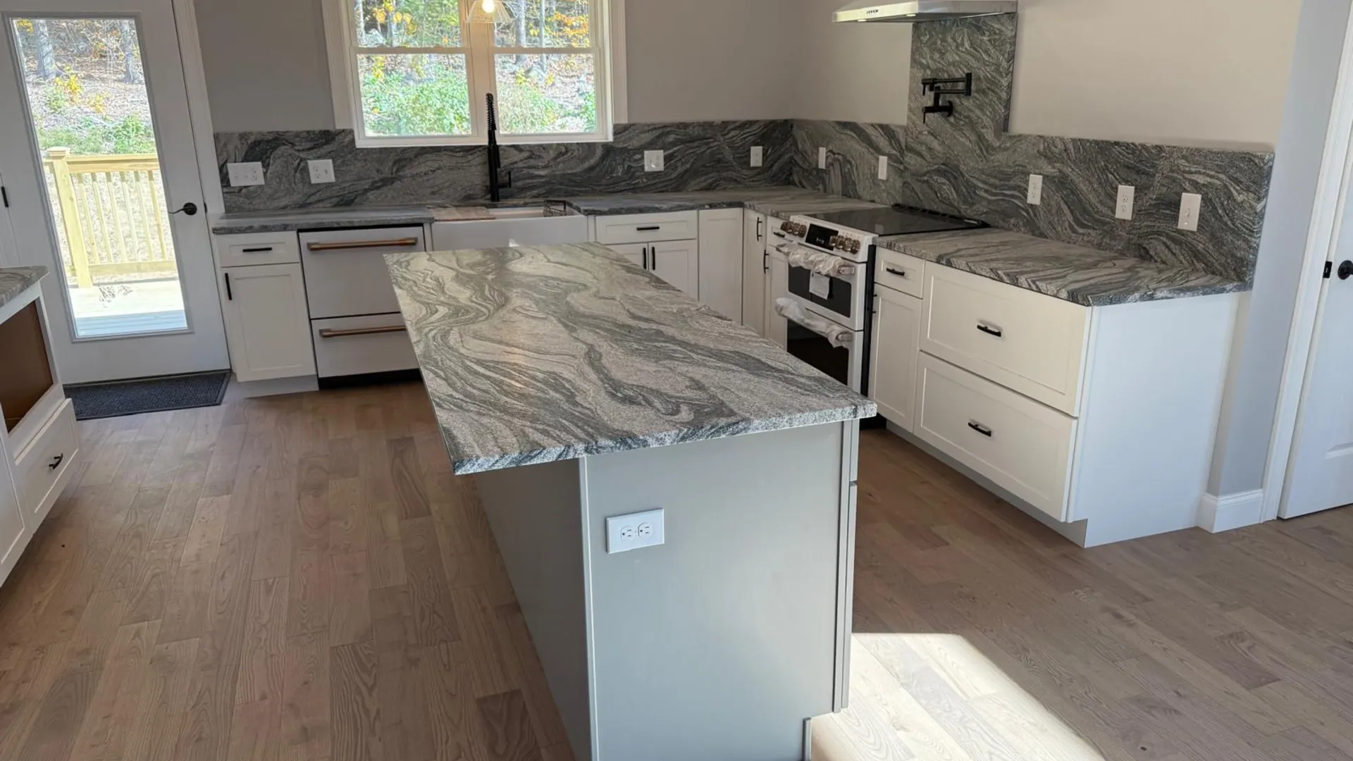 Finished New Hampshire kitchen with a stone island and full-height backsplash