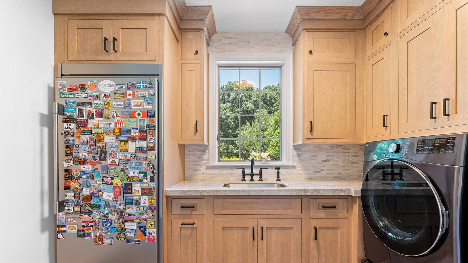 Warm wood kitchen with black pulls and a window-side sink