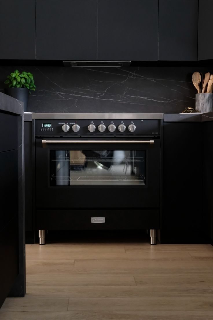 Black Verona range with a black marble backsplash and dark cabinets