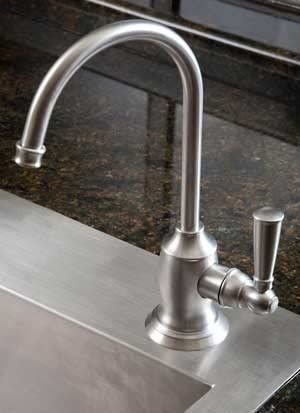 Brushed metal cold water dispenser on a steel counter