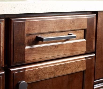Rich wood kitchen drawers with bronze pulls and pale countertop