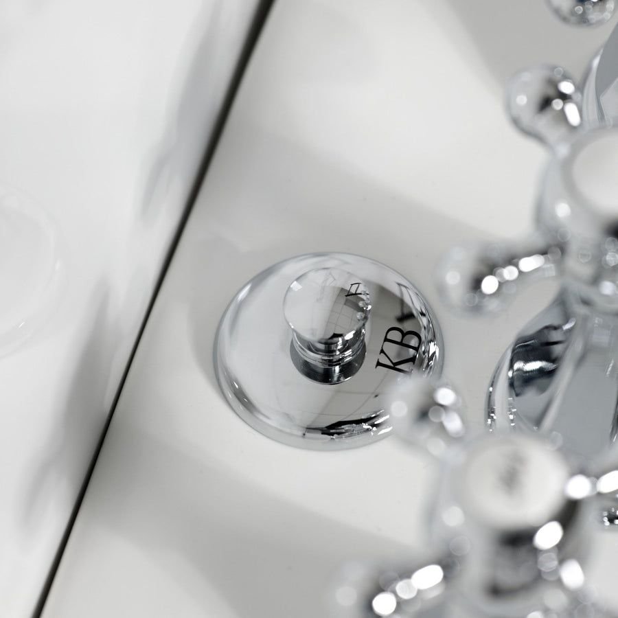 Polished chrome bidet faucet with three handles on white porcelain