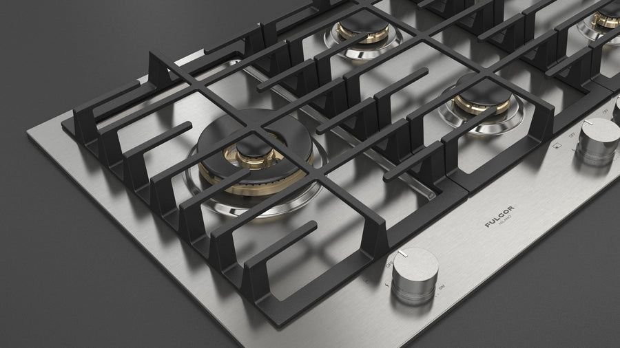 Matte black gas cooktop with brass burners and steel knobs