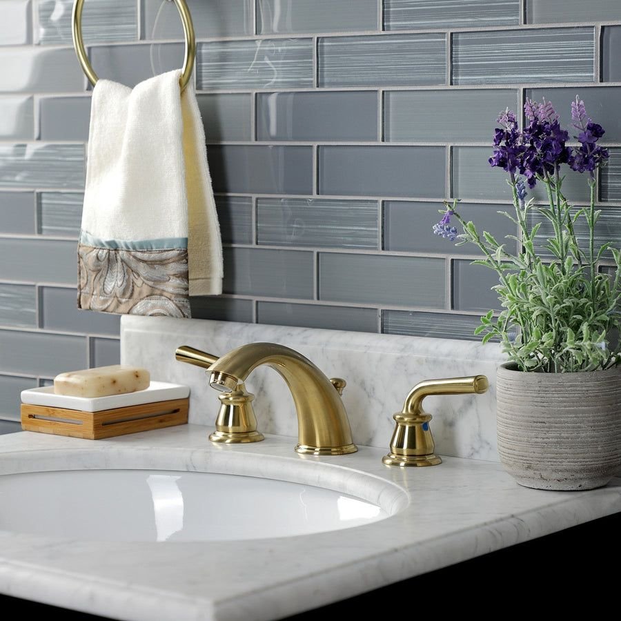 Gray tile bathroom vanity with brass widespread faucet
