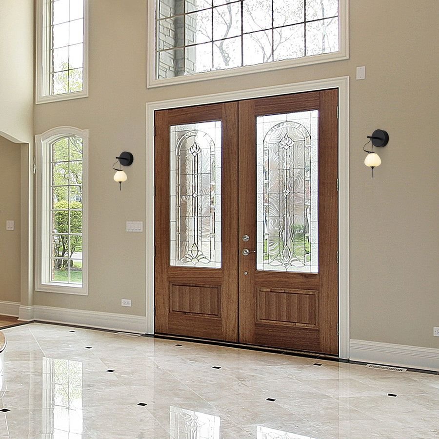Carved wood entry doors with black globe wall sconces