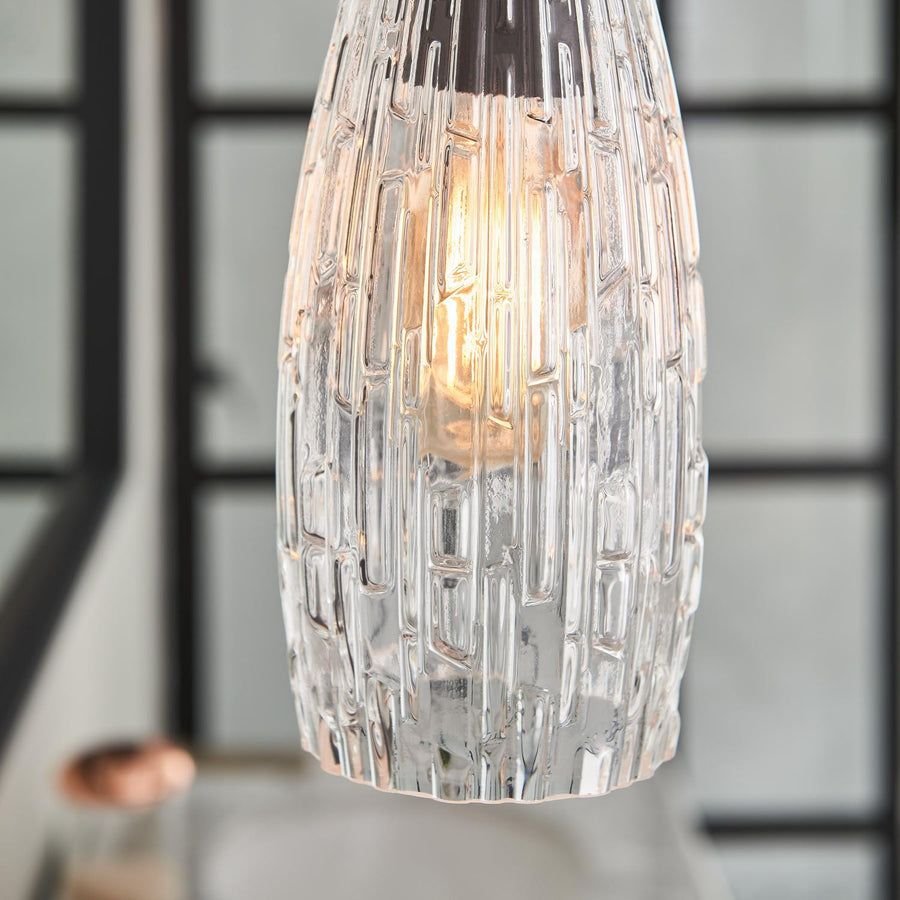 Clear glass pendant with sculpted texture and warm glow