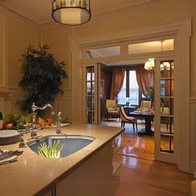 An undermount stainless kitchen sink with a bridge faucet in a warm traditional kitchen