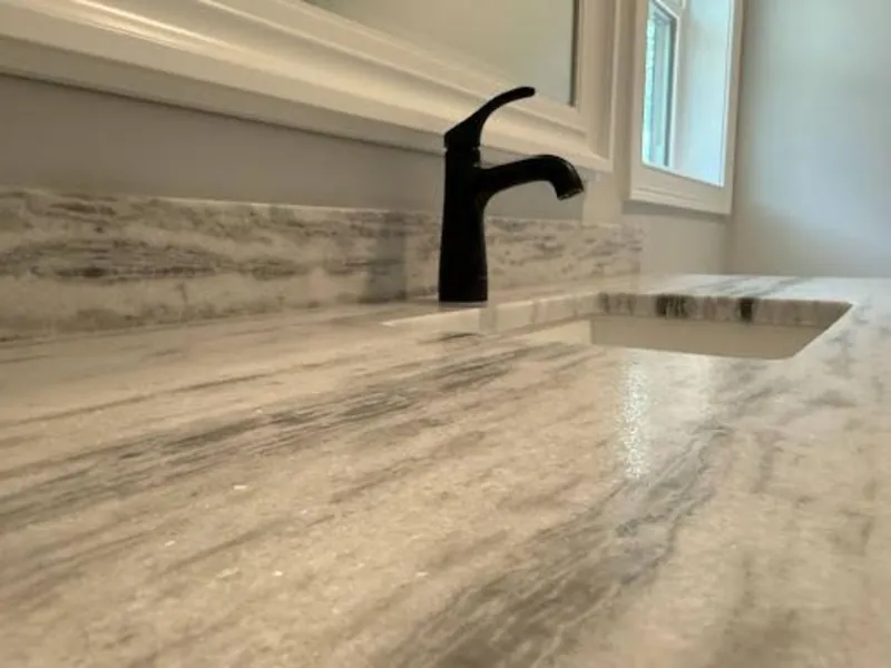 A renovated laundry room with a stone folding counter and a utility faucet