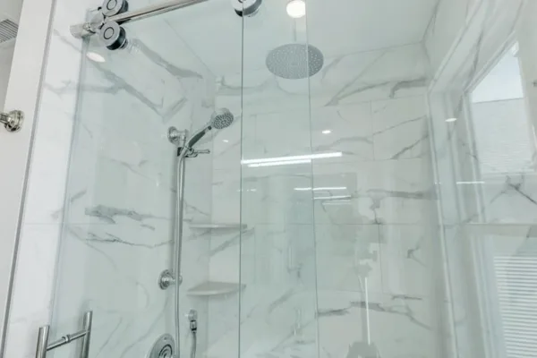 Marble-look porcelain shower with a frameless glass enclosure